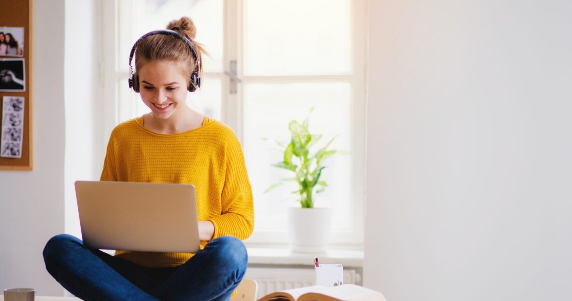 A,Young,Female,Student,Sitting,At,The,Table,,Using,Headphones