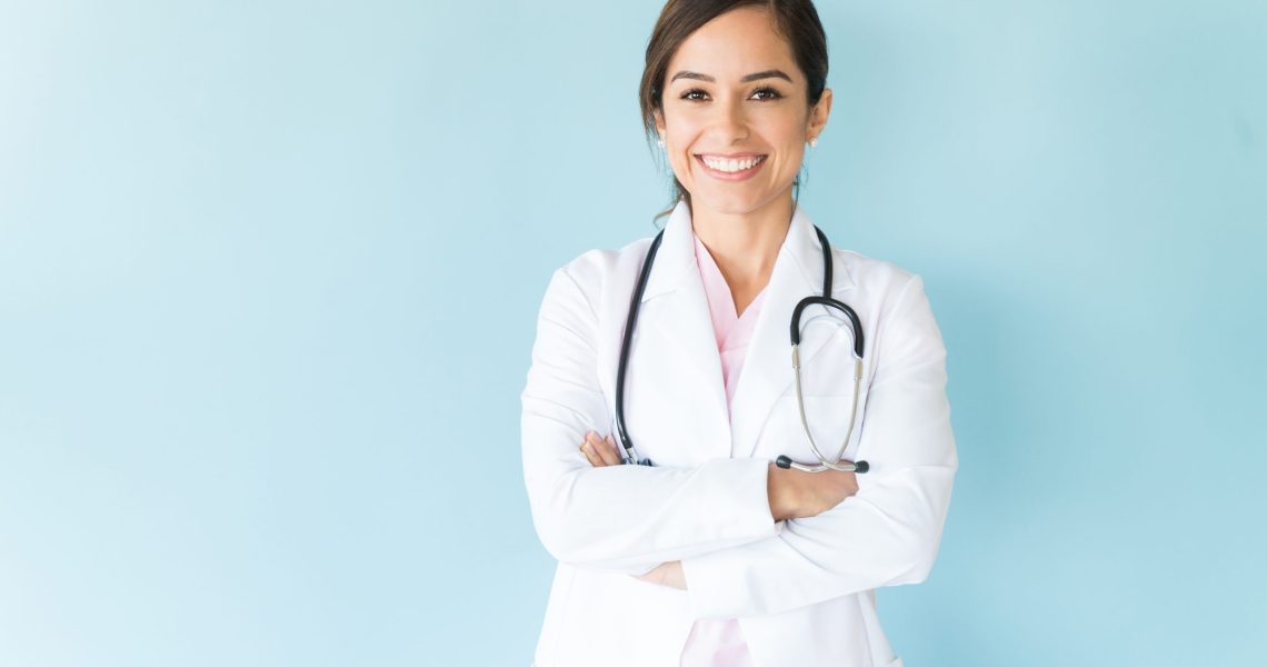 Smiling,Female,Doctor,In,Lab,Coat,With,Arms,Crossed,Against