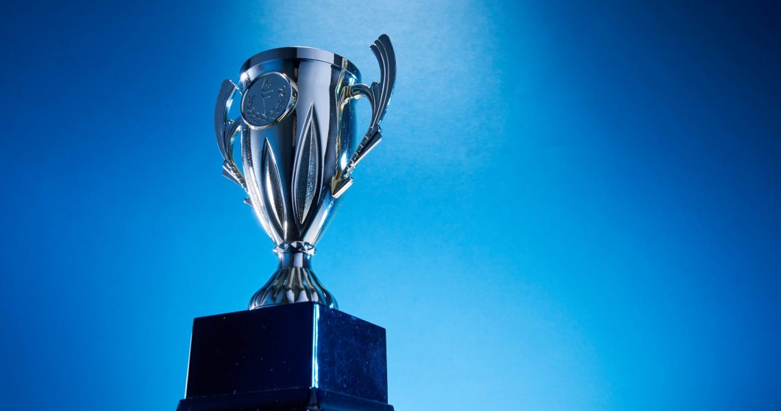 Low,Angle,View,Of,Winning,Trophy,Against,Blue,Background