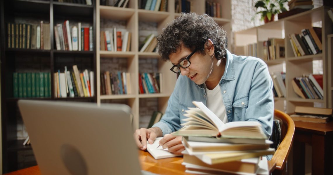 Student,Is,Doing,Research,At,Library,Using,His,Laptop,And