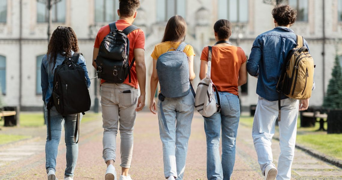 Group,Of,Five,Students,With,Backpacks,Walking,At,University,Campus