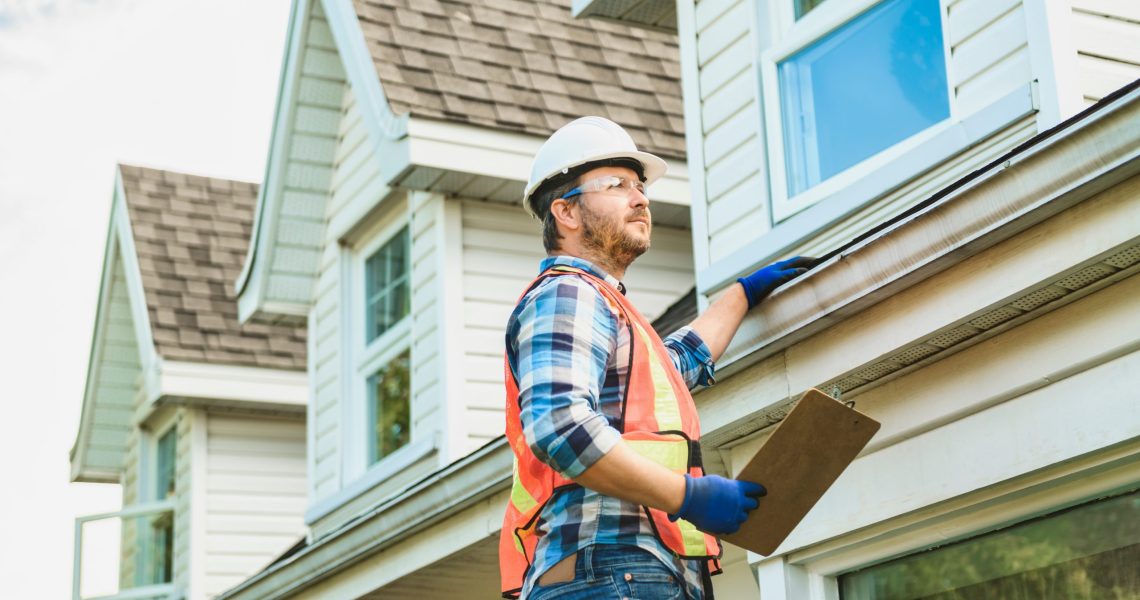 A,Man,With,Hard,Hat,Standing,On,Steps,Inspecting,House