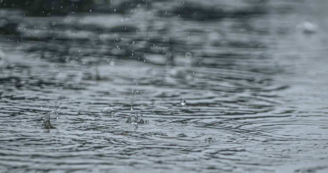 Close,Up,Of,Raindrops,Falling,On,A,Water,Surface,,Creating