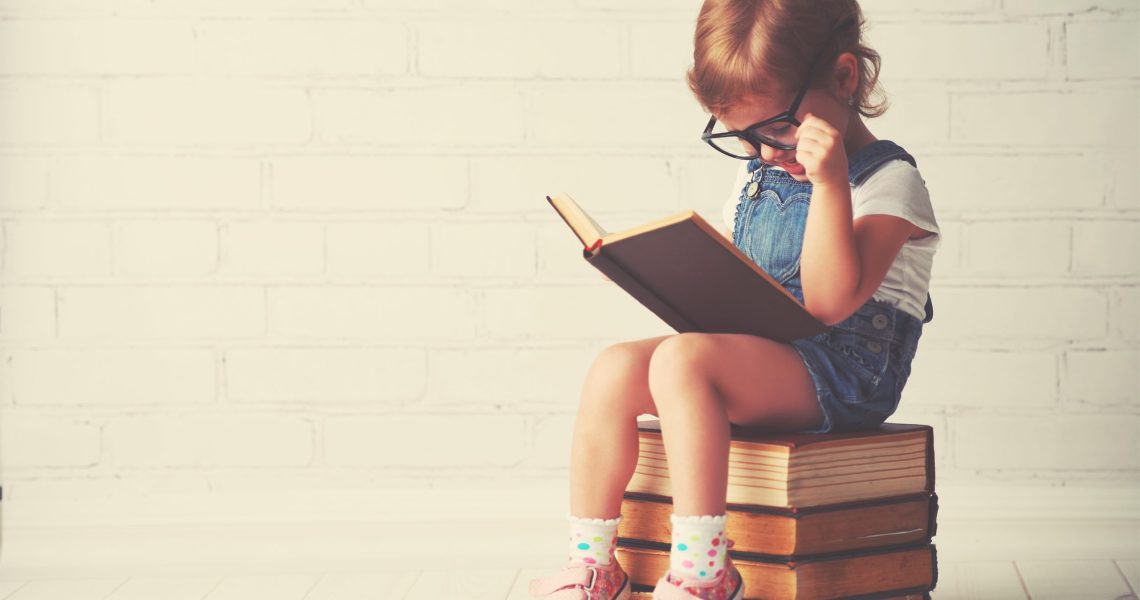 Happy,Child,Little,Girl,With,Glasses,Reading,A,Books
